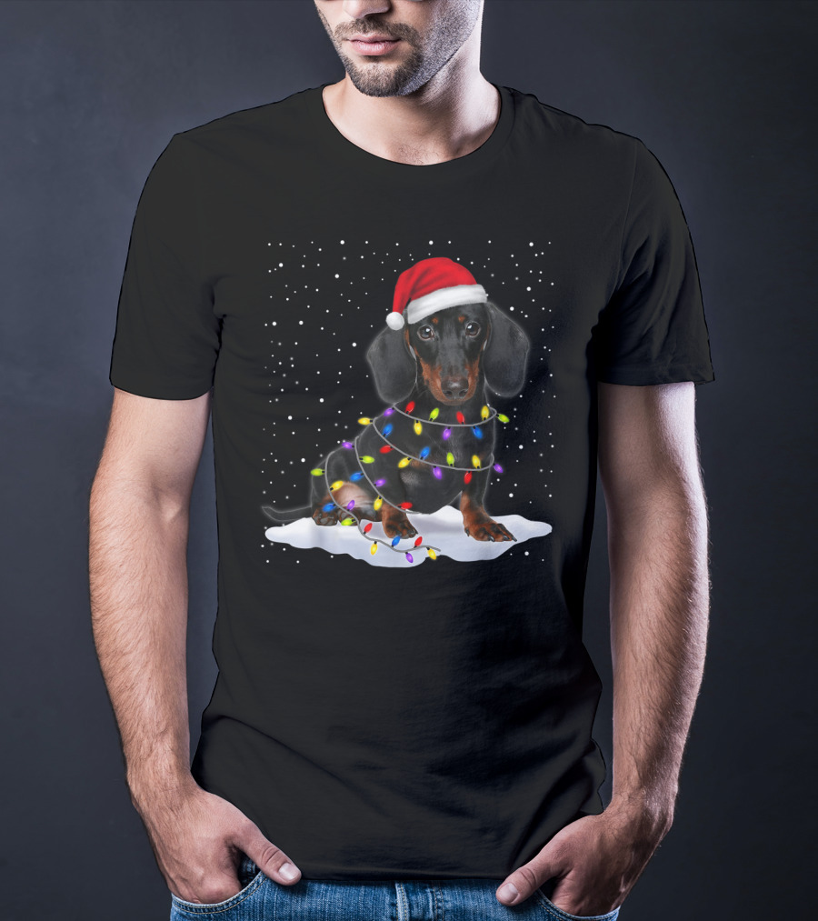 Dachshund Santa Hat Wrapped In Christmas Tree Lights In Snow With Falling Snowflakes T-Shirt