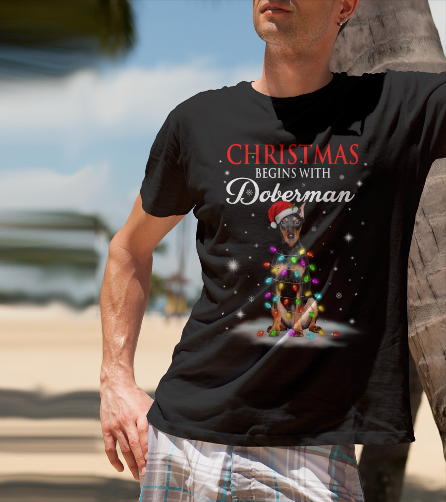 Christmas Begins With Doberman Wrapped In Holiday Lights And Santa Hat Snowflakes T-Shirt