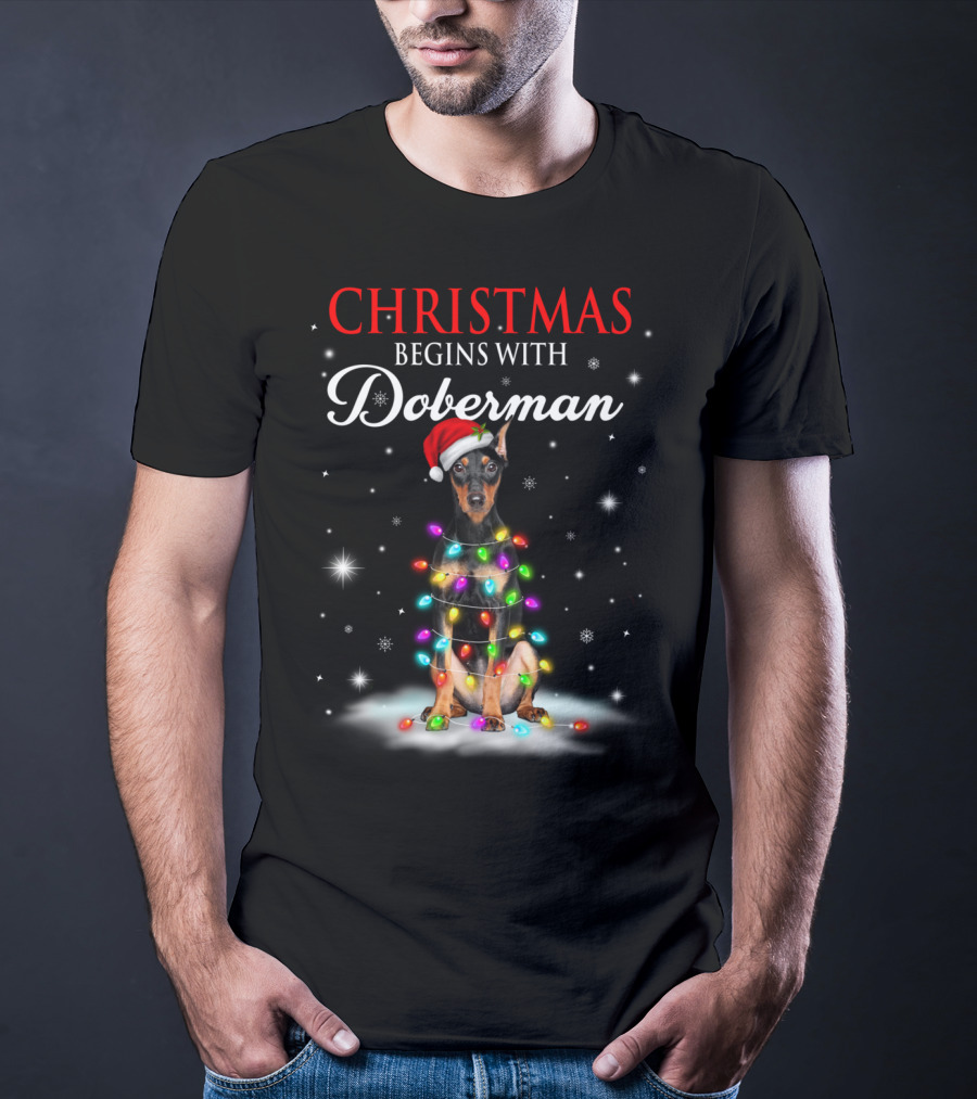 Christmas Begins With Doberman Wrapped In Holiday Lights And Santa Hat Snowflakes T-Shirt